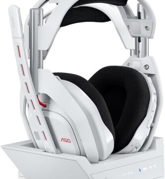 Auriculares gaming blancos Logitech Astro A50 sobre su base de carga inalámbrica junto a mandos de consola